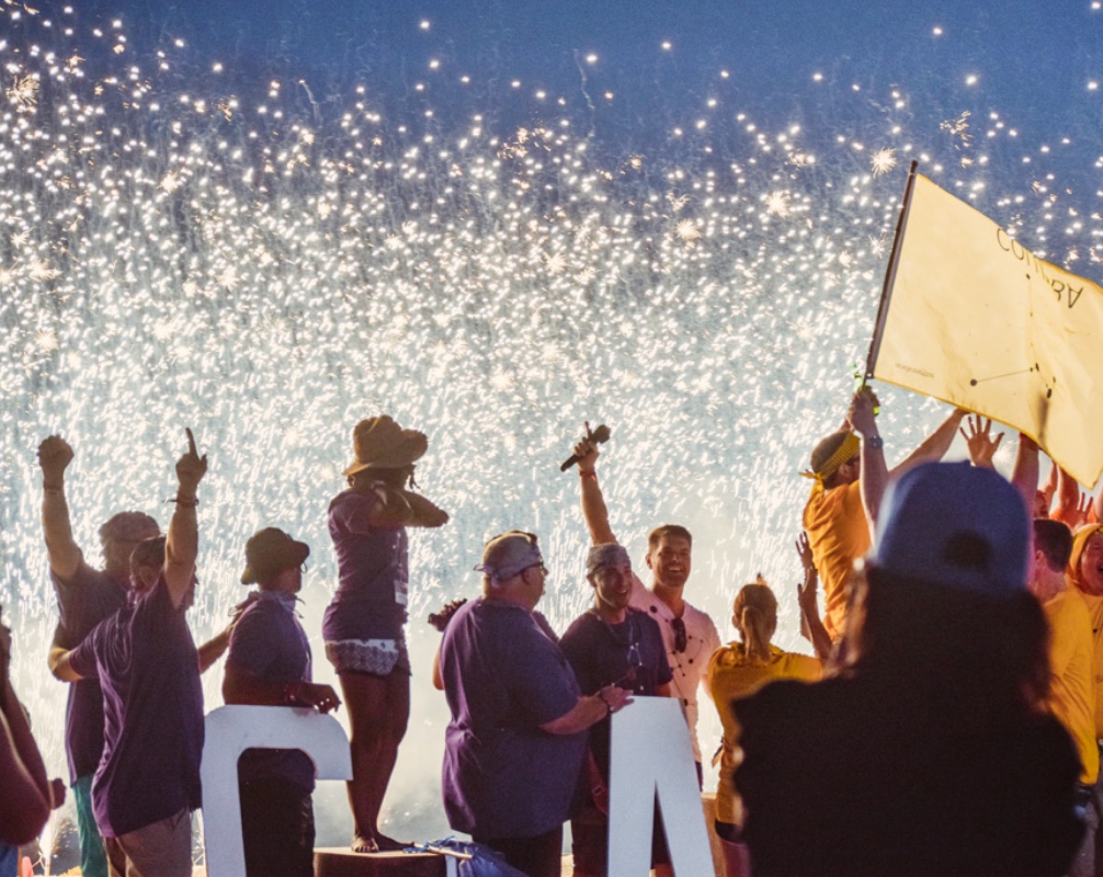 Group of Employees Celebrating with Fireworks in Background at Work Event